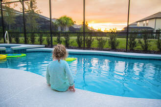 Picture of a girl sitting with her feet in a screen enclosed pool overlooking the sunset in Oviedo.